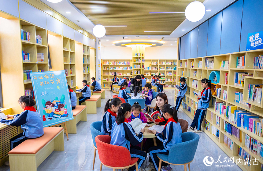 呼和浩特市玉泉區南柴火市街小學青年教師在校園圖書館輔導學生們閱讀。丁根厚攝