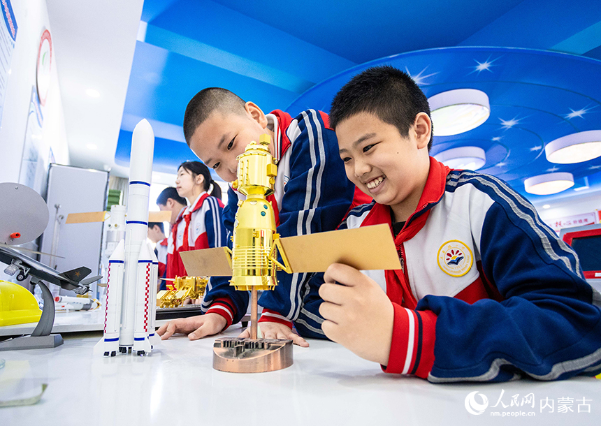 呼和浩特市玉泉區石東路小學學生在中國航天日主題科普活動中近距離觀看航天器模型。丁根厚攝