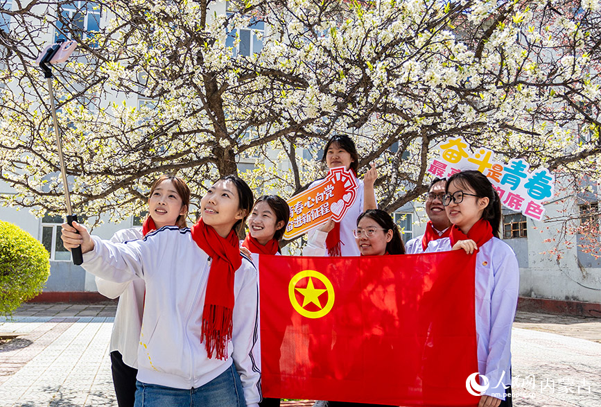 4月30日，内蒙古师范大学的青年团员手持团旗在“奋斗底色 青春绽放”诗歌朗诵会活动现场留影。丁根厚摄