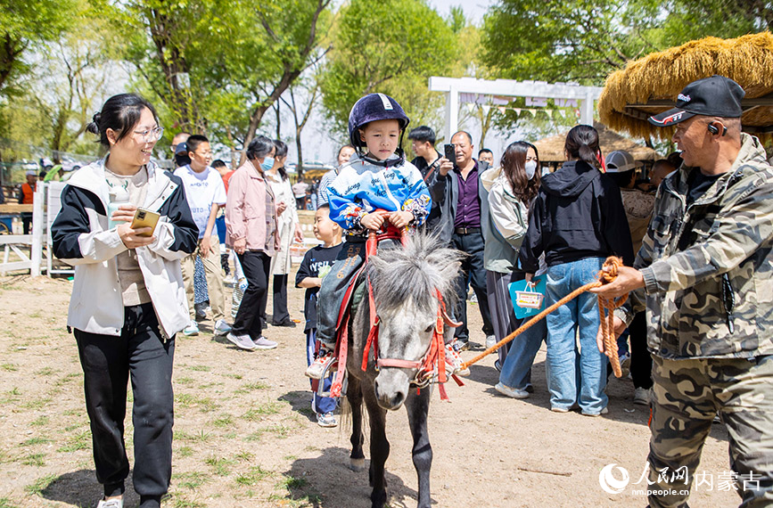 5月2日，家長陪伴孩子在呼和浩特玉泉區大黑河郊野公園萌寵樂園內騎矮馬。丁根厚攝