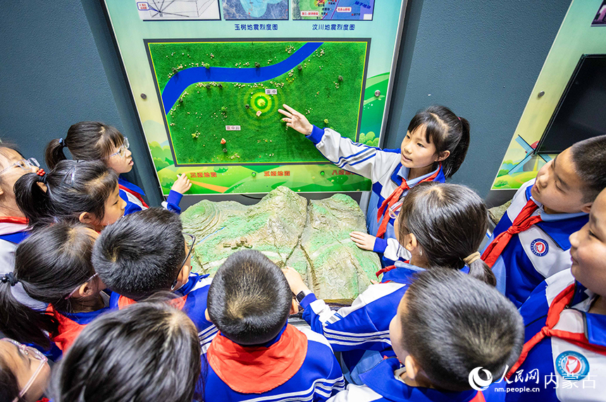 內蒙古呼和浩特市玉泉區通順街小學學生在地震科普館通過演示裝置了解地震知識。丁根厚攝