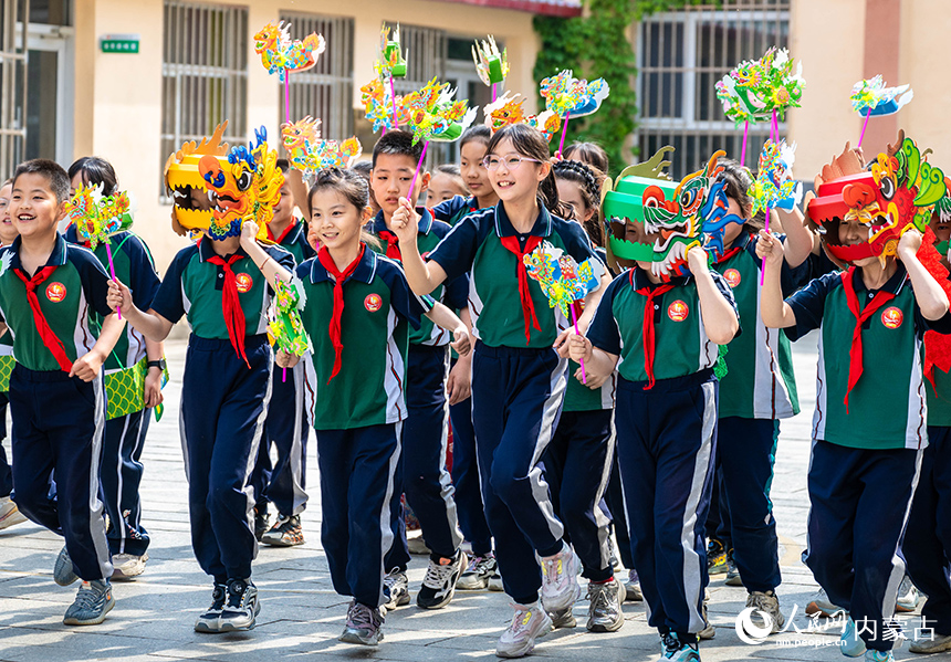 内蒙古呼和浩特市玉泉区恒昌店巷小学学生在“缤纷端午 粽享童趣”主题活动现场参加趣味龙舟风车赛。丁根厚摄