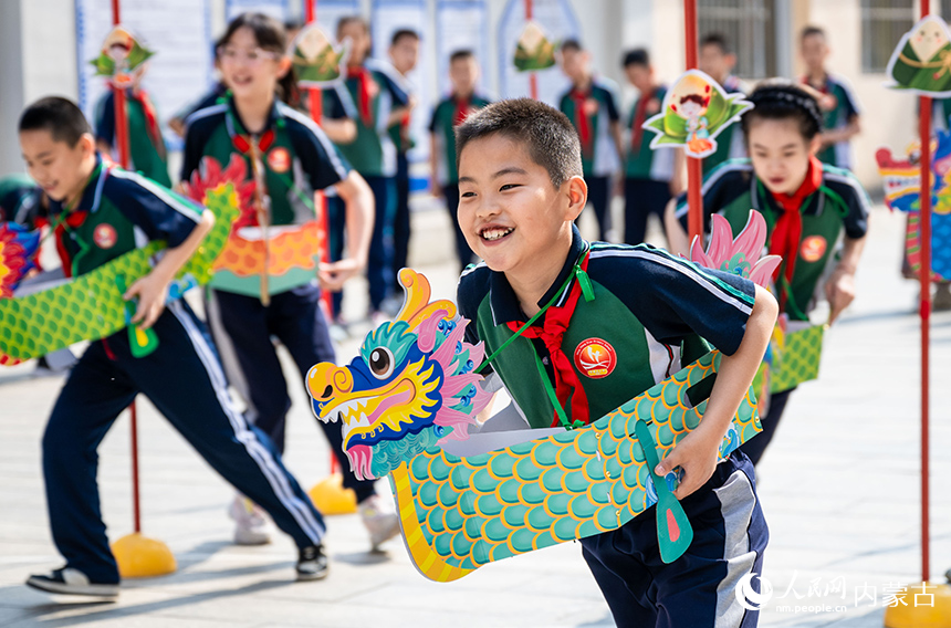 内蒙古呼和浩特市玉泉区恒昌店巷小学学生在“缤纷端午 粽享童趣”主题活动现场参加趣味龙舟赛。丁根厚摄