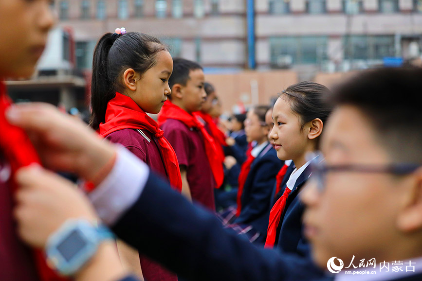五年级的少先队员为新队员佩戴红领巾，并送上祝福。人民网记者 李睿摄