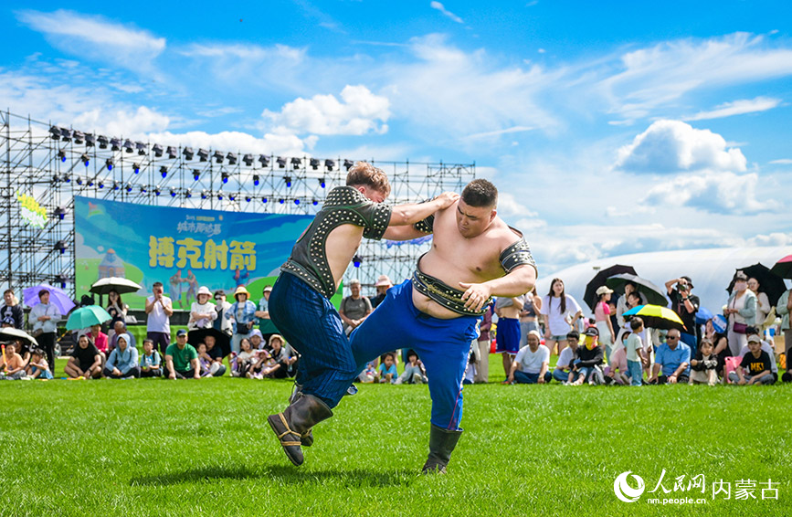 7月5日，游客在呼和浩特城市那达慕活动现场观看搏克比赛。丁根厚摄