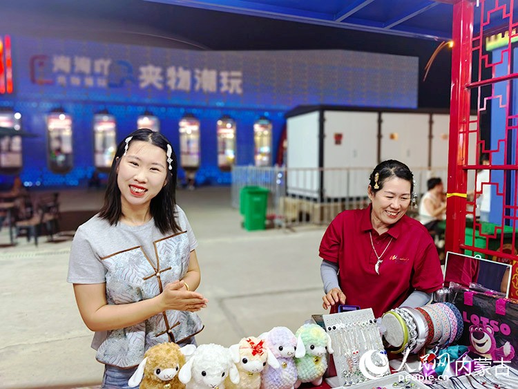 在民族手工艺品摊位，摊主戴着自己制作的饰品。众多商品让游客有多种选择。人民网记者 富丽娟摄