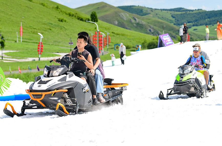 7月11日，游客在呼伦贝尔市牙克石市凤凰山景区的雪地上感受雪地摩托的速度与激情。王正摄
