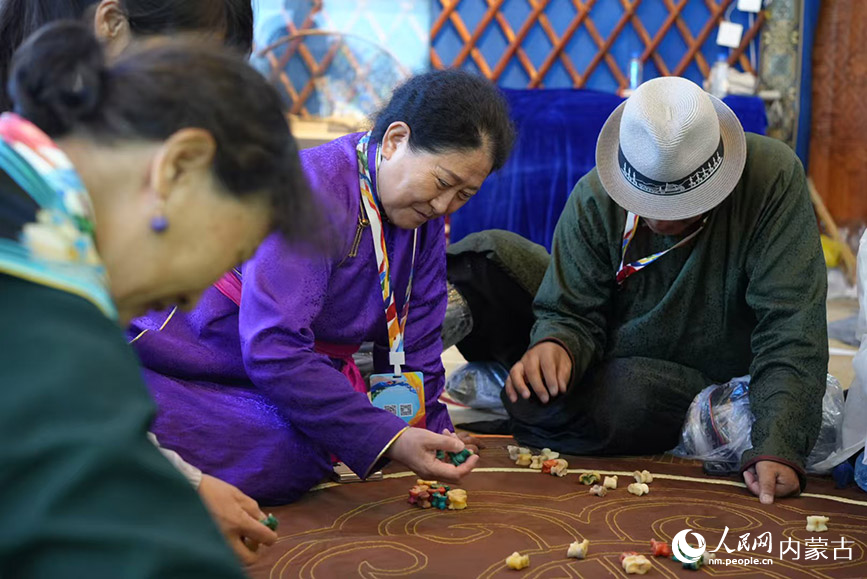 牧民与游客围坐一起玩传统游戏。人民网记者 李睿摄