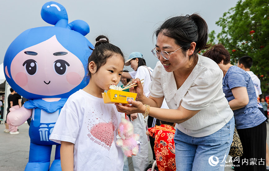 7月19日，游客在呼和浩特烧卖美食季活动现场品尝刚刚出笼的烧卖。丁根厚摄