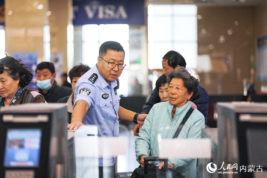 二连出入境边防检查站移民管理警察协助老年旅客办理通关手续。郭鹏杰摄