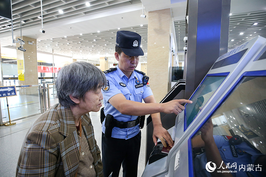 二连出入境边防检查站移民管理警察协助老年旅客办理通关手续。郭鹏杰摄