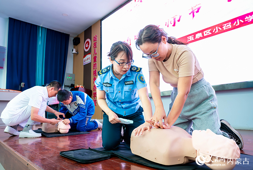 医护人员在呼和浩特市玉泉区小召小学指导师生练习心肺复苏技能。丁根厚摄