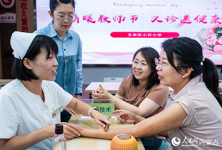 医护人员在呼和浩特市玉泉区小召小学为老师们做刮痧治疗。丁根厚摄