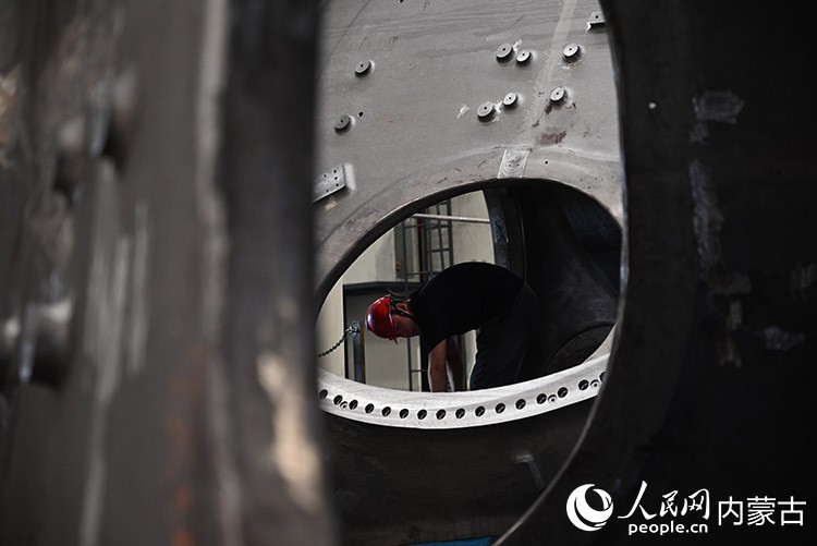 工人进入到轮毂内部，进行人工打磨。人民网记者 刘艺琳摄