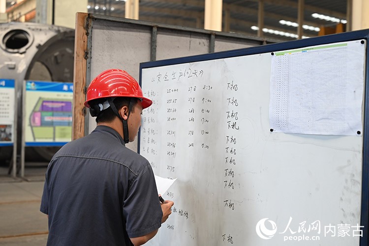 工人正在提示板上记录着各个机床上设备的安全生产时间。人民网记者 刘艺琳摄