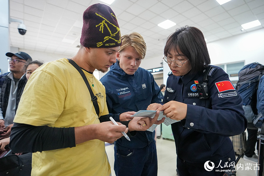 二连出入境边防检查站移民管理警察正在为入境旅客提供通关咨询。杨金烨摄