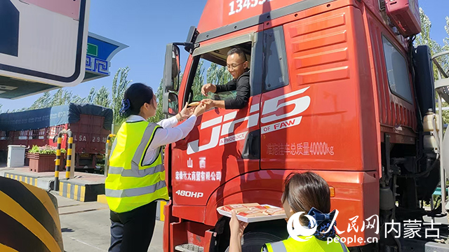10月6日，內蒙古交通集團巴彥淖爾分公司臨河新區收費所工作人員將月餅送到貨車司機手中。內蒙古自治區交通運輸廳供圖