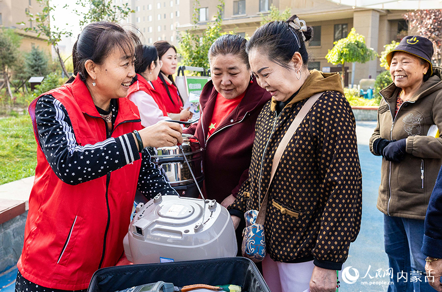 呼和浩特市玉泉區“文明市集”主題活動現場，志願者在為社區居民修理小家電。丁根厚攝