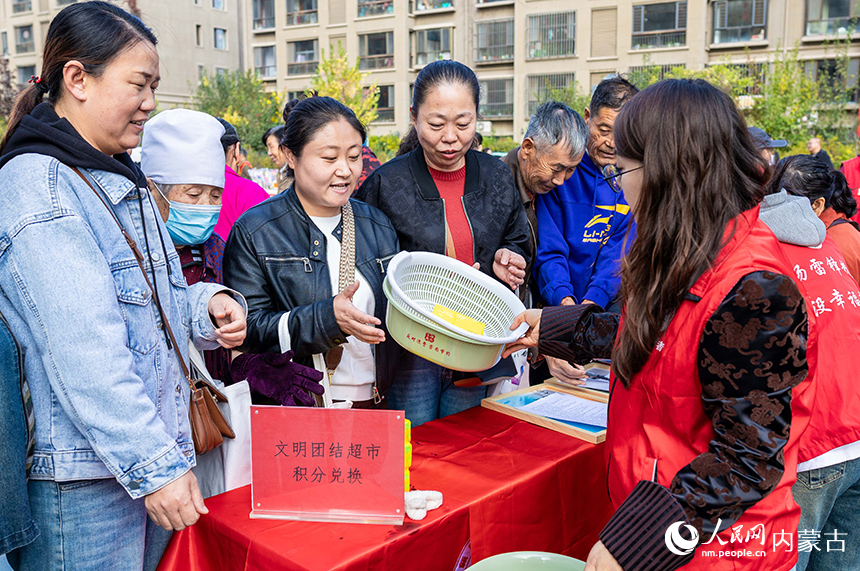 呼和浩特市玉泉區“文明市集”主題活動現場，社區居民用平日積攢的“民族團結積分”兌換日用品。丁根厚攝