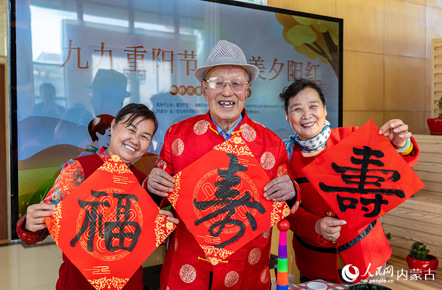 老人们手持“寿”字在呼和浩特市玉泉区民政局“爱心敬老 情暖重阳”主题活动现场留影。丁根厚摄