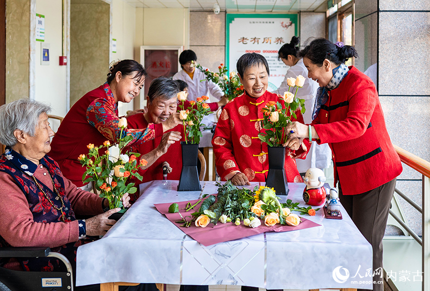 老人们在呼和浩特市玉泉区民政局“爱心敬老 情暖重阳”主题活动现场体验插花花艺。丁根厚摄