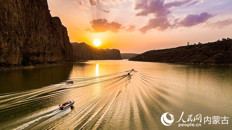 夕阳下游船在老牛湾黄河大峡谷驶过。王劭凯摄