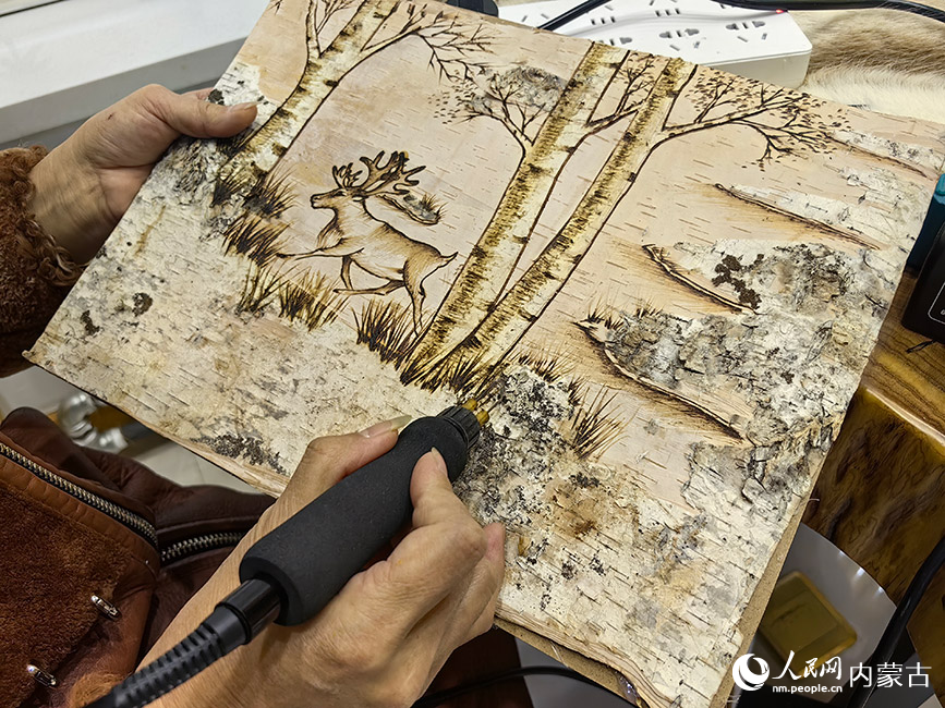 敖鲁古雅太阳城文创市集内手工艺传承者在制作桦树皮画。人民网记者 富丽娟摄