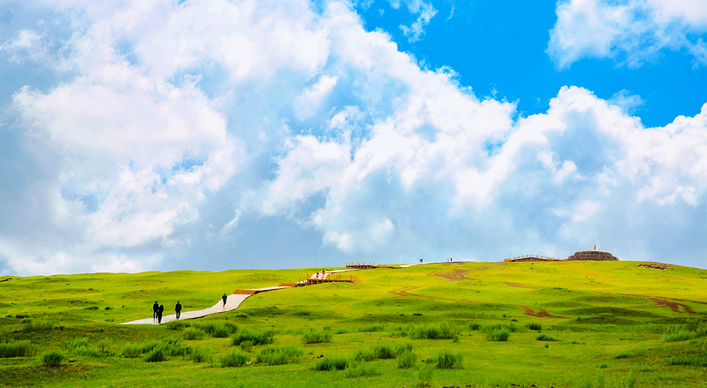 登頂淖爾梁，遠山疊翠銜著流雲，腳下草甸綿延至天際。