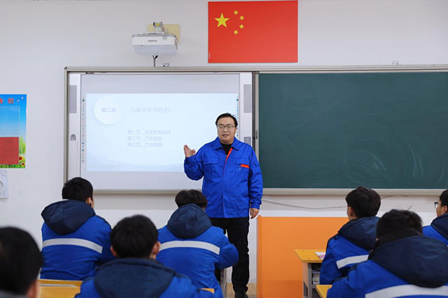 呂建強站在教室講台前，面向學生講授《汽車文化》課，課堂氛圍專注而濃厚。劉新平攝