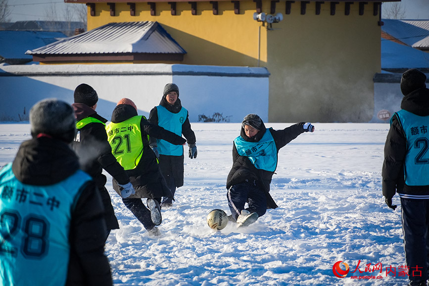 額爾古納市第二中學的學生在雪地中奔跑爭球，身影躍動，雪花飛濺。實習生 牛佳攝