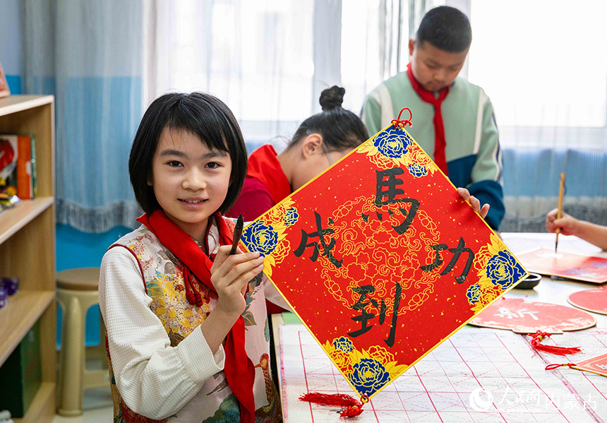 呼和浩特市玉泉区恒昌店巷小学学生在展示自己书写的“马到成功”迎新年主题书法作品。丁根厚摄