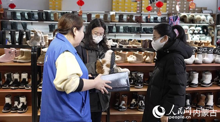 门店售货员正在和顾客介绍靴子。李青迪摄