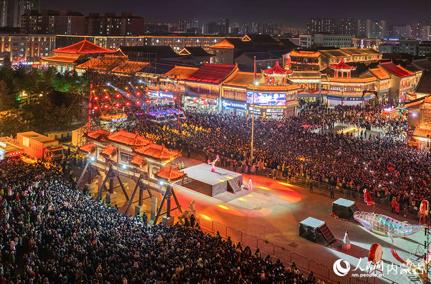 市民和游客在呼和浩特市玉泉区塞上老街旅游休闲街区跨年夜活动现场观看表演。丁根厚摄