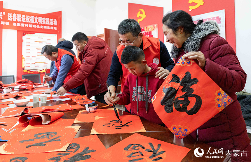 呼和浩特市玉泉區文化科技衛生“三下鄉”集中示范活動現場，文化志願者教小朋友書寫“福”字。丁根厚攝