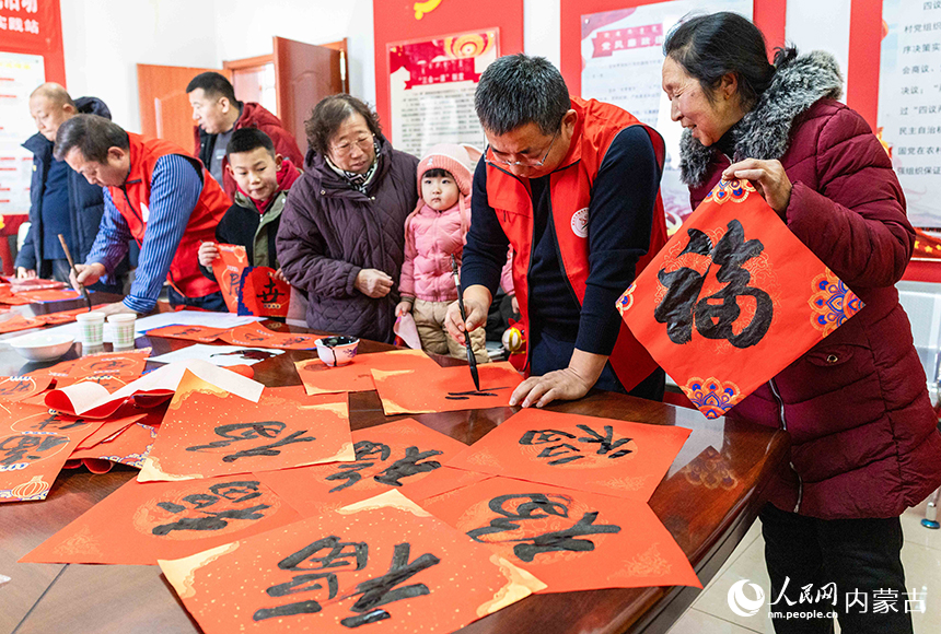 呼和浩特市玉泉區文化科技衛生“三下鄉”集中示范活動現場，文化志願者為群眾書寫“福”字和春聯，送祝福。丁根厚攝
