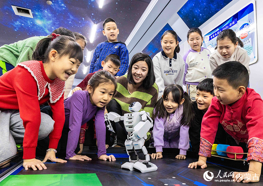 孩子们在呼和浩特市玉泉区青少年宫与智能机器人开心互动。丁根厚摄