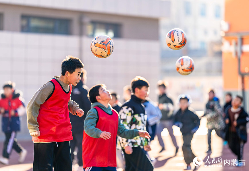 2月1日，呼和浩特市玉泉区南茶坊小学校园足球冬训活动现场，小球员们在绿茵场上进行头球训练。丁根厚摄