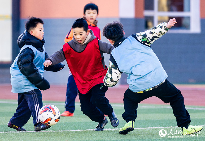 2月1日，呼和浩特市玉泉区南茶坊小学校园足球冬训活动现场，小球员们在绿茵场上进行足球分组对抗赛。丁根厚摄
