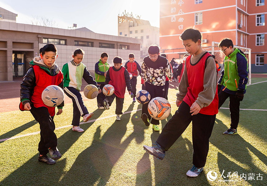 2月1日，呼和浩特市玉泉区南茶坊小学校园足球冬训活动现场，小球员们在绿茵场上进行足球基本功训练。丁根厚摄