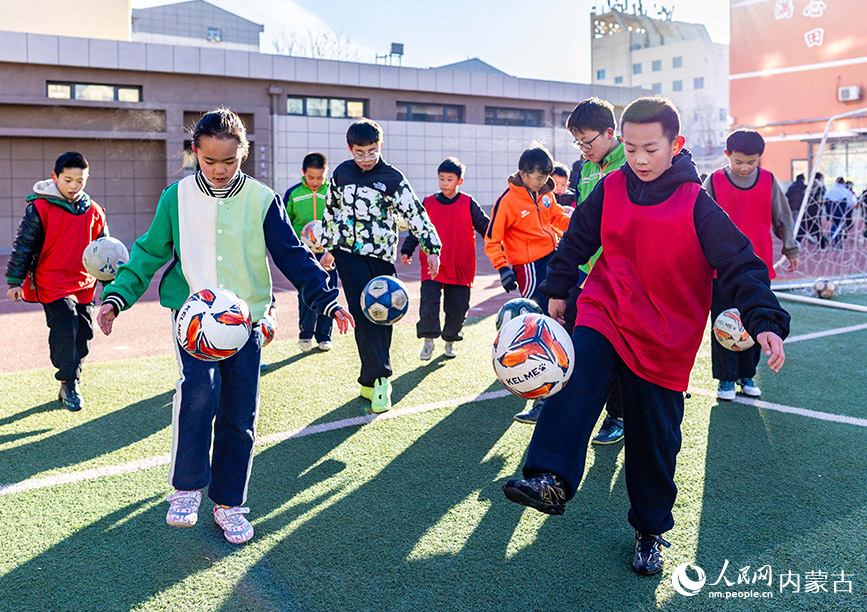 2月1日，呼和浩特市玉泉区南茶坊小学校园足球冬训活动现场，小球员们在绿茵场上进行颠球训练。丁根厚摄