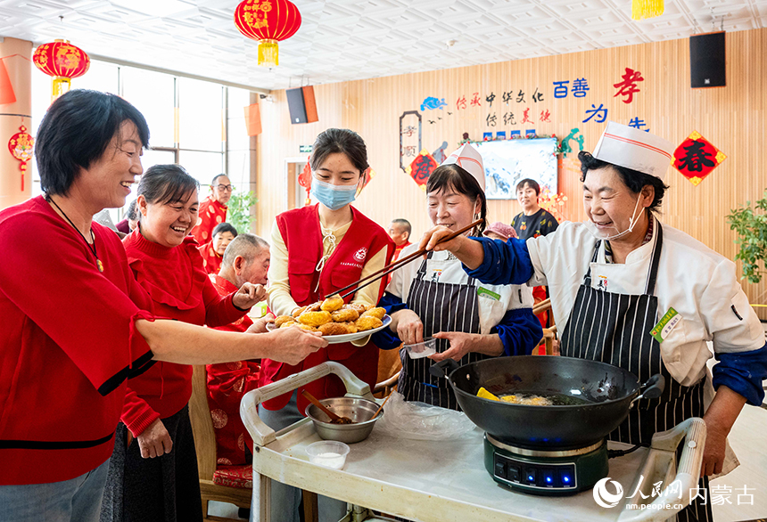 呼和浩特市玉泉区民政局的志愿者和工作人员为老人们做油炸糕。丁根厚摄