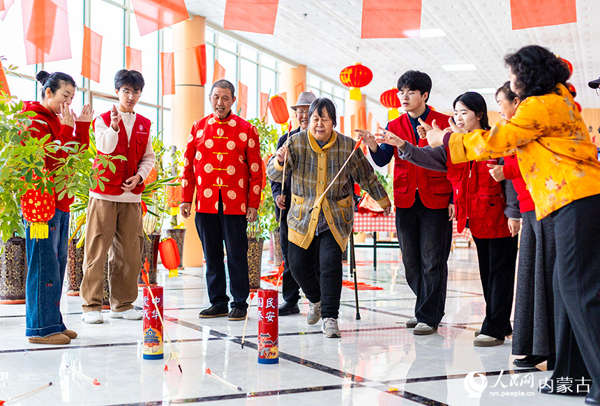 呼和浩特市玉泉区民政局的青年志愿者与老人们在玩投壶游戏。丁根厚摄