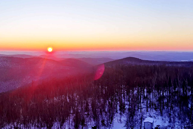 晨光笼罩着层层覆雪的山峦,景色十分壮美。