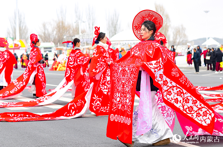 模特在鄂尔多斯市2026年群众迎春年俗巡游活动中表演鄂尔多斯剪纸服装秀。王正摄