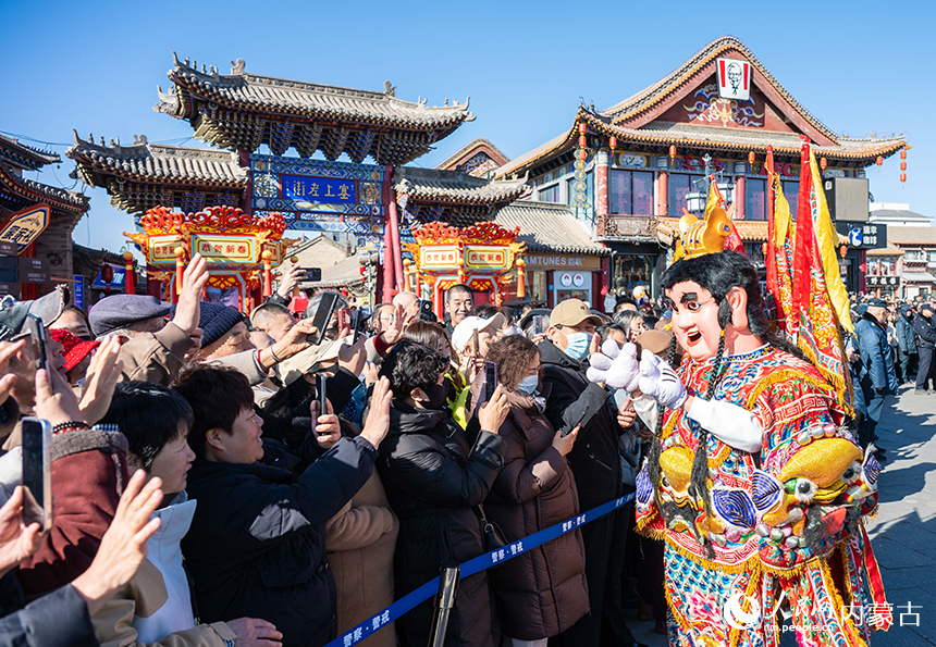 呼和浩特新春文化廟會非遺“鬧元宵”活動現場，表演電音三太子的演員與游人互動。丁根厚攝