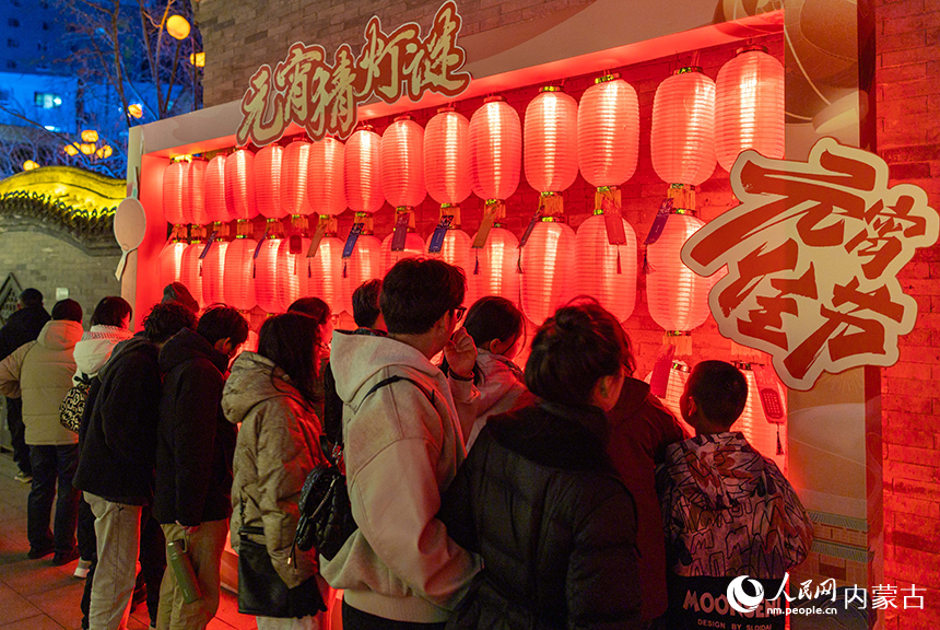 呼和浩特市玉泉區“鯉燈映月 福滿上元”魚燈夜游會現場，游人在猜燈謎。丁根厚攝