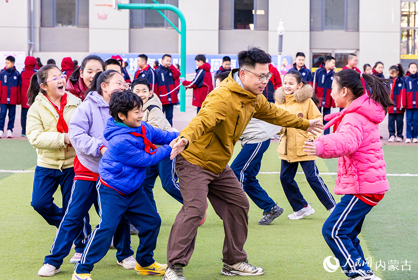 呼和浩特市玉泉区石东路小学师生在操场玩老鹰抓小鸡趣味游戏。丁根厚摄