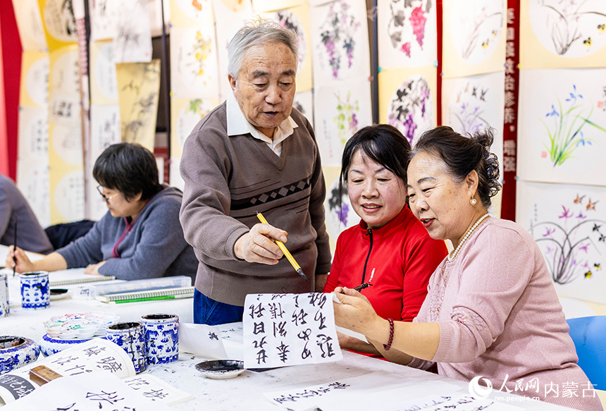 老年學員在玉泉區老年大學書法課上交流書法技藝。丁根厚攝