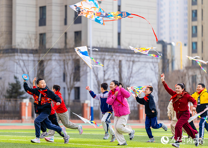 呼和浩特市玉泉区恒昌店巷小学五里营校区的学生在操场上放飞风筝，感受春天的气息。丁根厚摄
