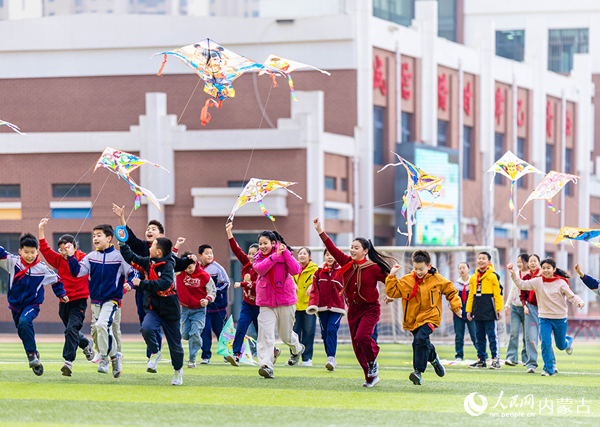 呼和浩特市玉泉區恆昌店巷小學五裡營校區的學生在操場上放飛風箏，感受春天的氣息。丁根厚攝